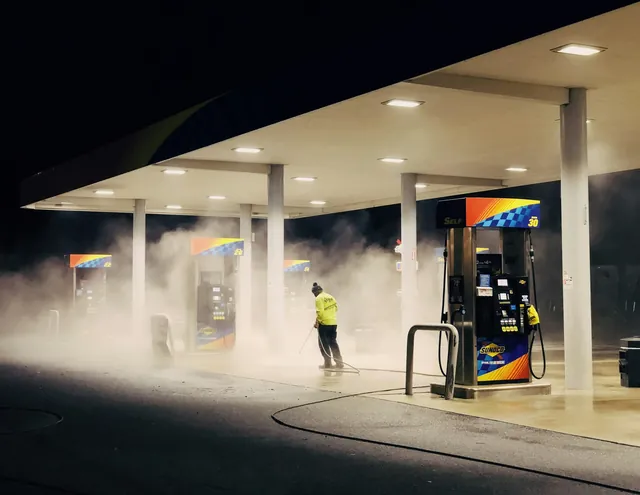 Operative pressure washing a commercial forecourt at night