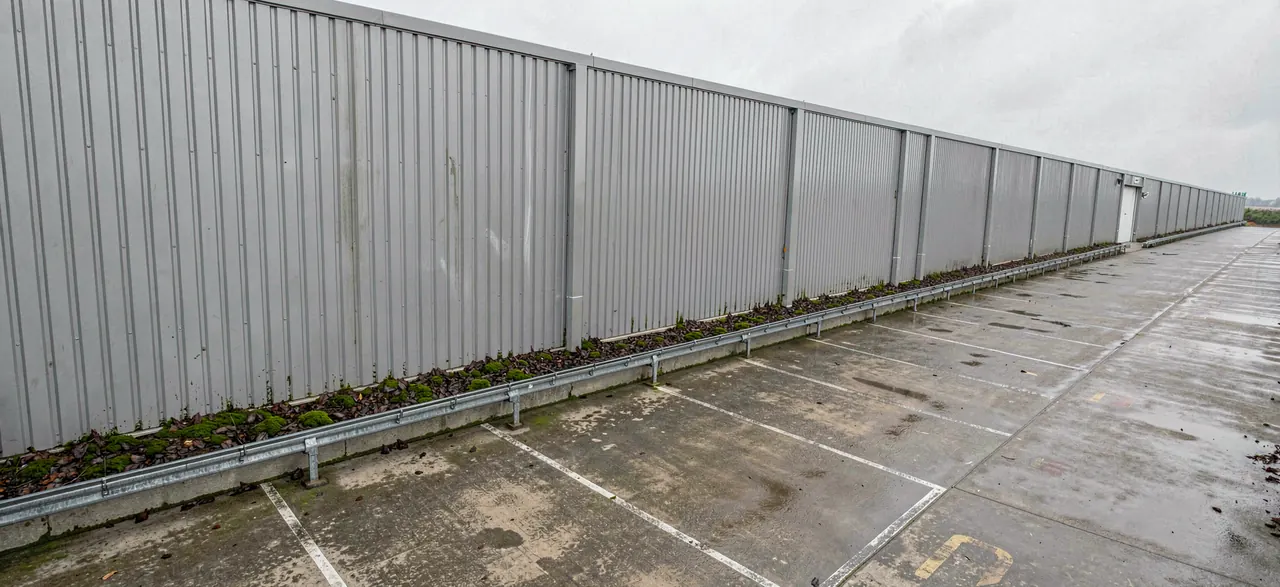 Moss and debris collected along the gutter line of a large clad commercial building